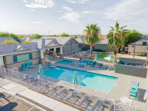our apartments have a swimming pool with chairs and palm trees at Villas on Olive, Peoria, Arizona