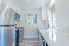 A modern kitchen with stainless steel appliances and white countertops.