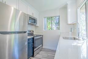 A kitchen with a stainless steel refrigerator, microwave, oven, and sink.