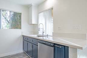 A kitchen with a white counter top and blue cabinets.