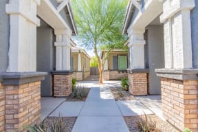 a walkway between two buildings with a tree in the middle at Villas on Olive, Peoria, Arizona