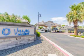 a villas on olive apartments entrance with a sign and palm trees at Villas on Olive, Peoria, Arizona
