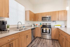 a kitchen with wooden cabinets and stainless steel appliances and a sink at Villas on Olive, Peoria, Arizona