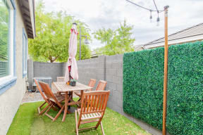 a backyard patio with a table and chairs and a privacy hedge at Villas on Olive, Peoria, Arizona 85345