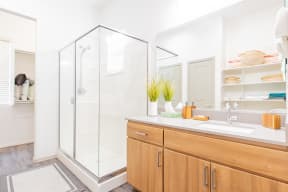 a bathroom with a shower and a sink and wooden cabinets at Villas on Olive, Peoria, Arizona