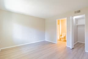 an empty living room with wood flooring and a toilet
