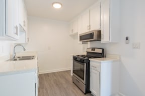 a kitchen with white cabinets and a stove and microwave