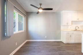 an empty kitchen with white cabinets and a ceiling fan