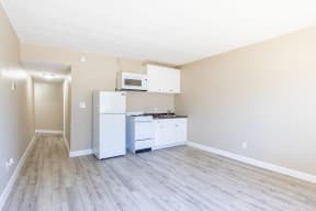 an empty kitchen with white appliances and a microwave and refrigerator