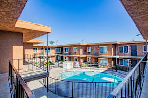 A pool in a courtyard surrounded by a black fence.