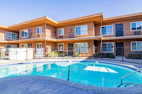 A swimming pool in front of a multi-story apartment building.
