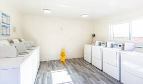 A yellow caution sign is on the floor of a laundry room.