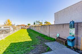 a yard with a fence and a green lawn next to a parking meter