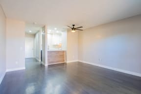 an empty living room with wood floors and a ceiling fan