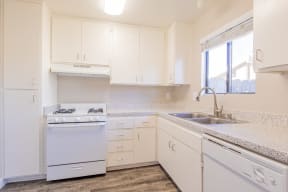 a kitchen with white cabinets and a sink and a window