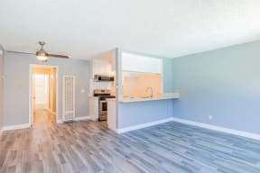 an empty living room and kitchen with a hard wood floor