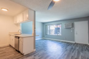 an empty living room with a kitchen and a window