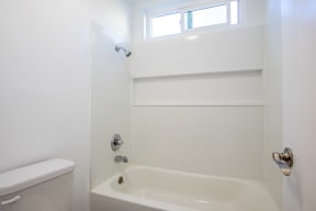 a bathroom with a tub and a toilet and a window