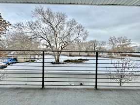 a view of a snow covered parking lot from behind a fence