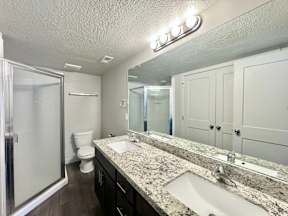 a bathroom with two sinks and a shower and a toilet
