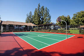 A red and green tennis court with a basketball hoop in the background at Metro 3610, Riverside, 92505