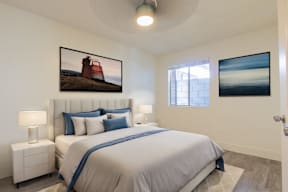 A bedroom with a large bed and two pictures on the wall.