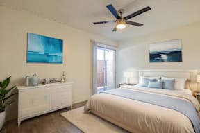 A bedroom with a large bed and a ceiling fan.