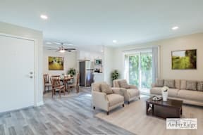 A spacious living room with a dining area and a kitchen in the background.