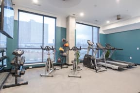 a gym with cardio machines and weights in a room with windows