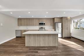 a kitchen with a large center island with a stove top oven and a refrigerator
