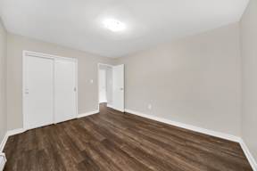 a bedroom with hardwood floors and white walls