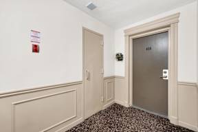 a hallway with a gray door and a carpeted floor