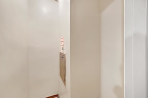 a small door in the wall of a room with white walls and a wooden floor