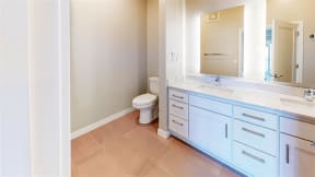 bathroom vanity with backlit mirror and tile floor