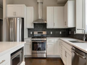 Penthouse kitchen with gas stove, hood and tile backsplash