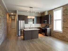 Kitchen and island with wood floors and exposed brick