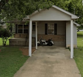 A small house with a covered porch and a motorcycle parked in front.