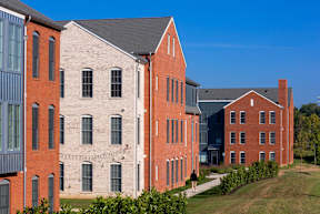 A red brick building with a black roof and a white building with a grey roof.