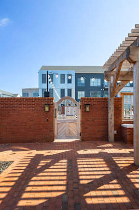 A blue building with a white door and a wooden pergola.
