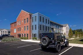 A black jeep is parked in a parking lot in front of a building.