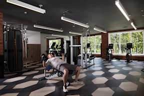 A man is working out in a gym with a checkered floor.