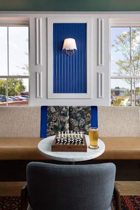 A blue and white framed picture with a lit candle on a table.