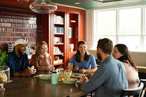 A group of people are sitting around a table eating popcorn.