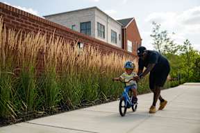 A man is teaching a young boy how to ride a bike.