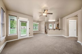 an empty living room with a ceiling fan and a window