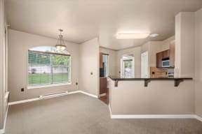 an empty living room and kitchen with a large window