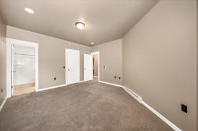 an empty living room with carpet and a door to a closet
