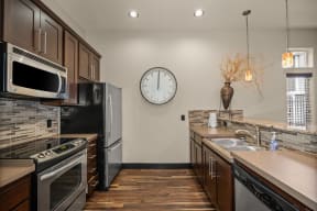 a kitchen with stainless steel appliances and a clock on the wall