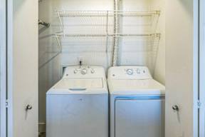 Two white washing machines in a small laundry room.