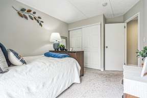 A bedroom with a large bed and a lamp on the side table.